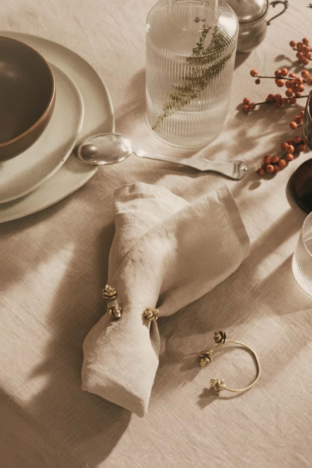 Close-up of linen napkin with gold napkin ring, fresh berries and warm-toned tablescape styling