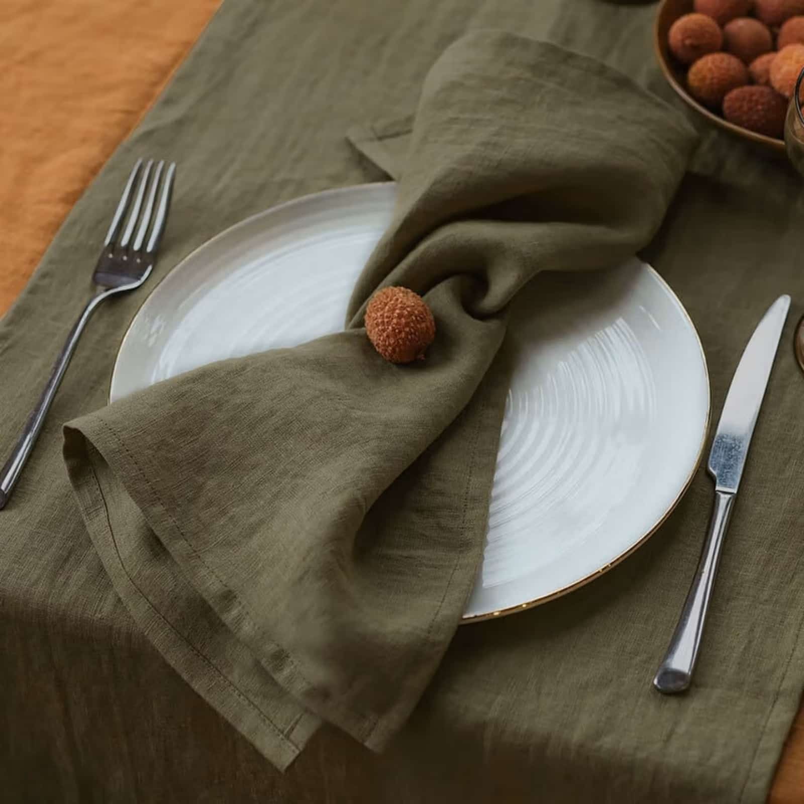 Olive green linen napkin with gold rim plate in dining setting