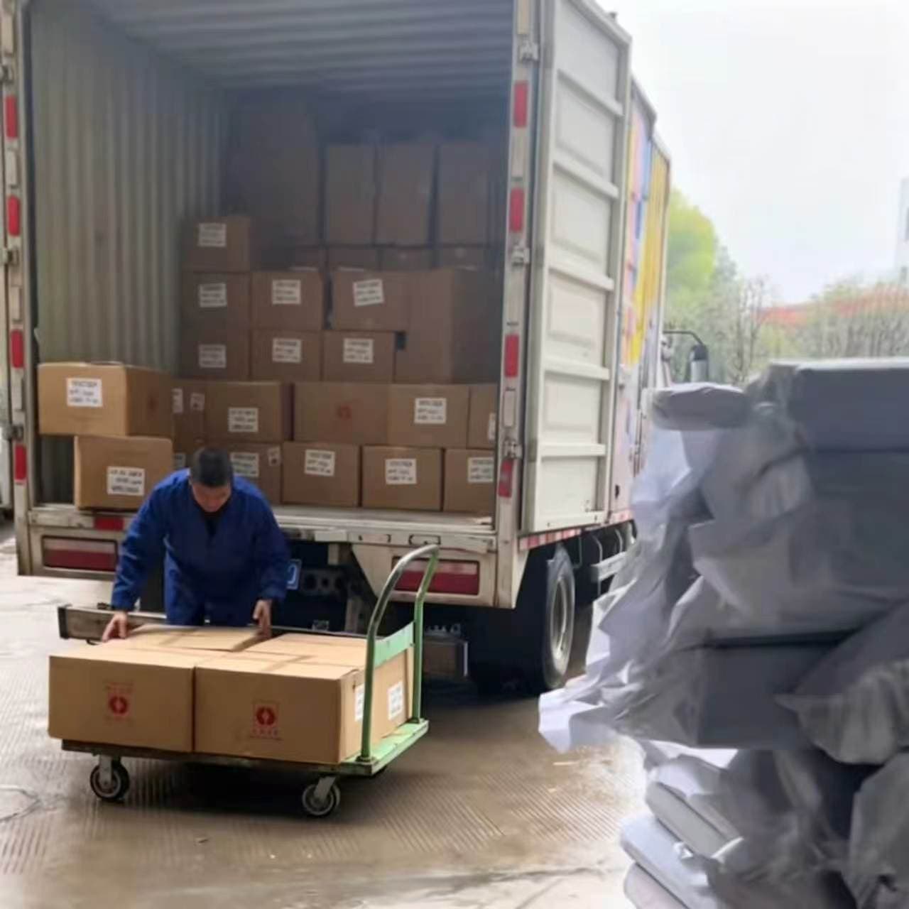 Linen bulk order unloaded from truck by handcart in rain