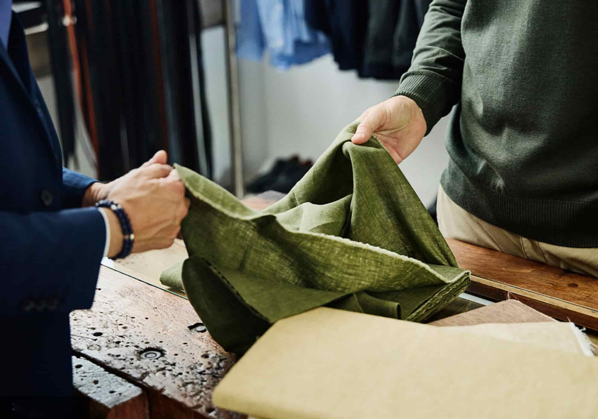 Two hands examining the drape and texture of premium washed European linen fabric in a workshop setting — part of Budloop's Standard Fabric Sample Pack experience.