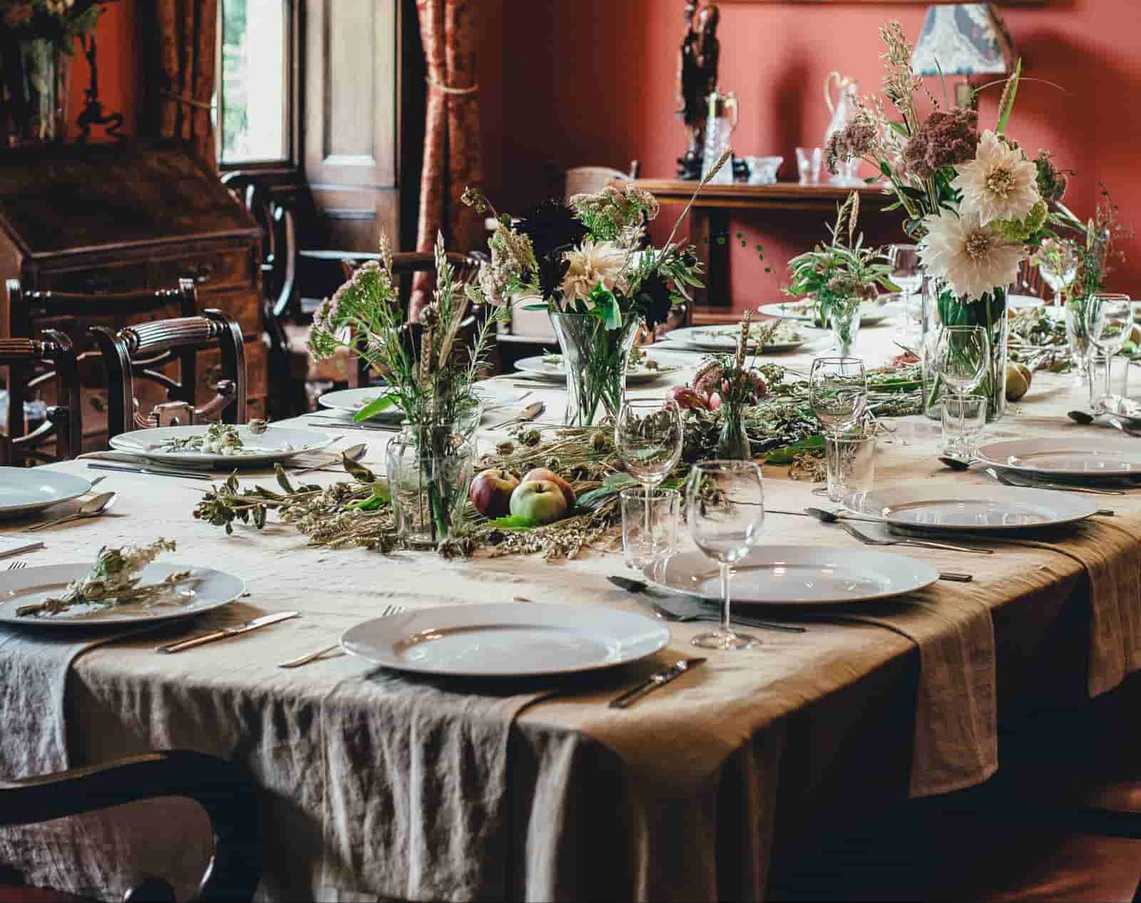 Vintage dining room with red walls, linen tablecloth, wildflower arrangements and apple table decor for formal dinner