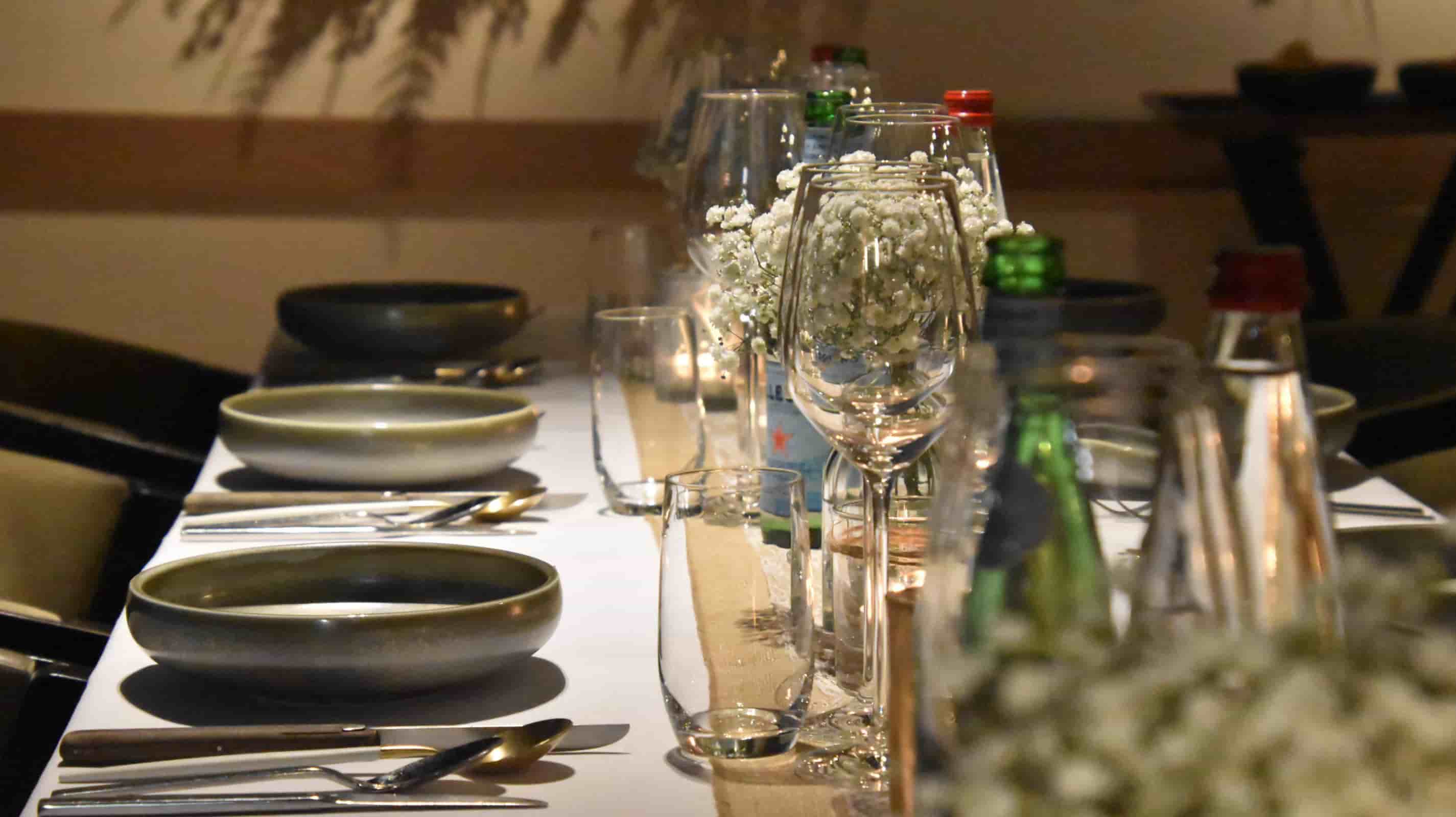 White linen tablecloth and burlap table runner on a long banquet table with matte ceramic plates and gypsophila floral centerpiece