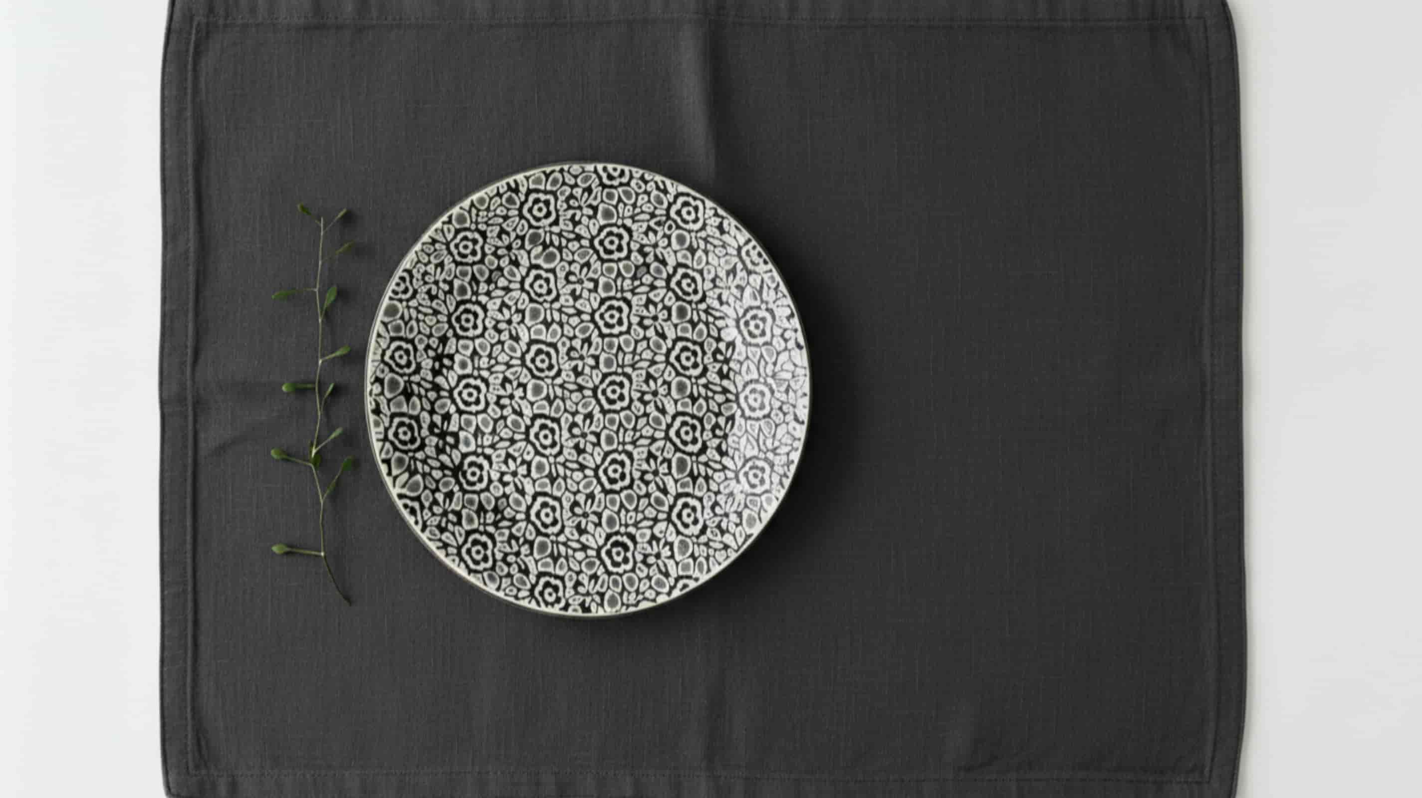 Dark grey linen placemat with ceramic plate overhead minimal