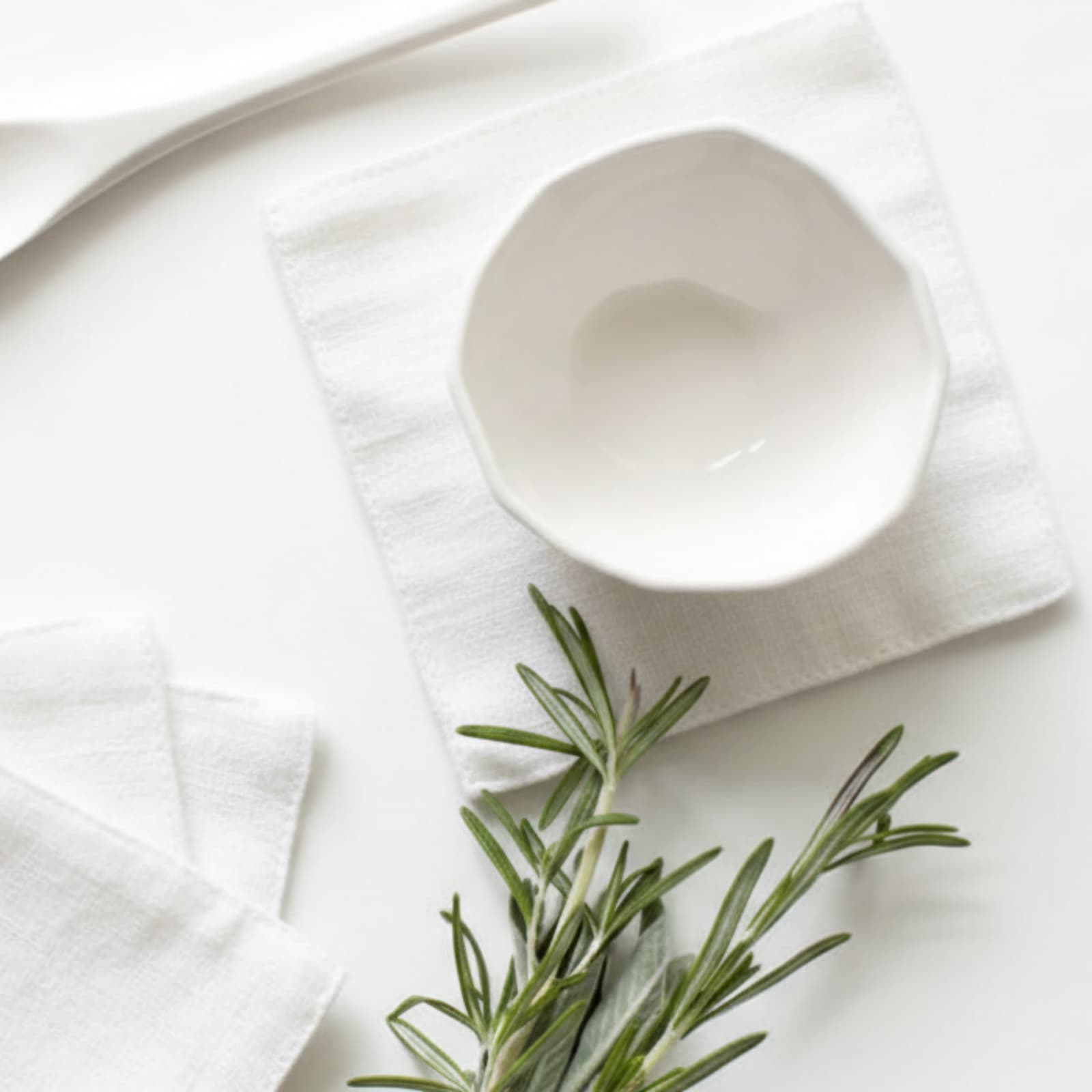 Budloop white linen cocktail napkins with clean solid-edge construction, styled with a minimalist ceramic bowl and rosemary, showcasing premium double-layer seamless quality for hospitality tables.